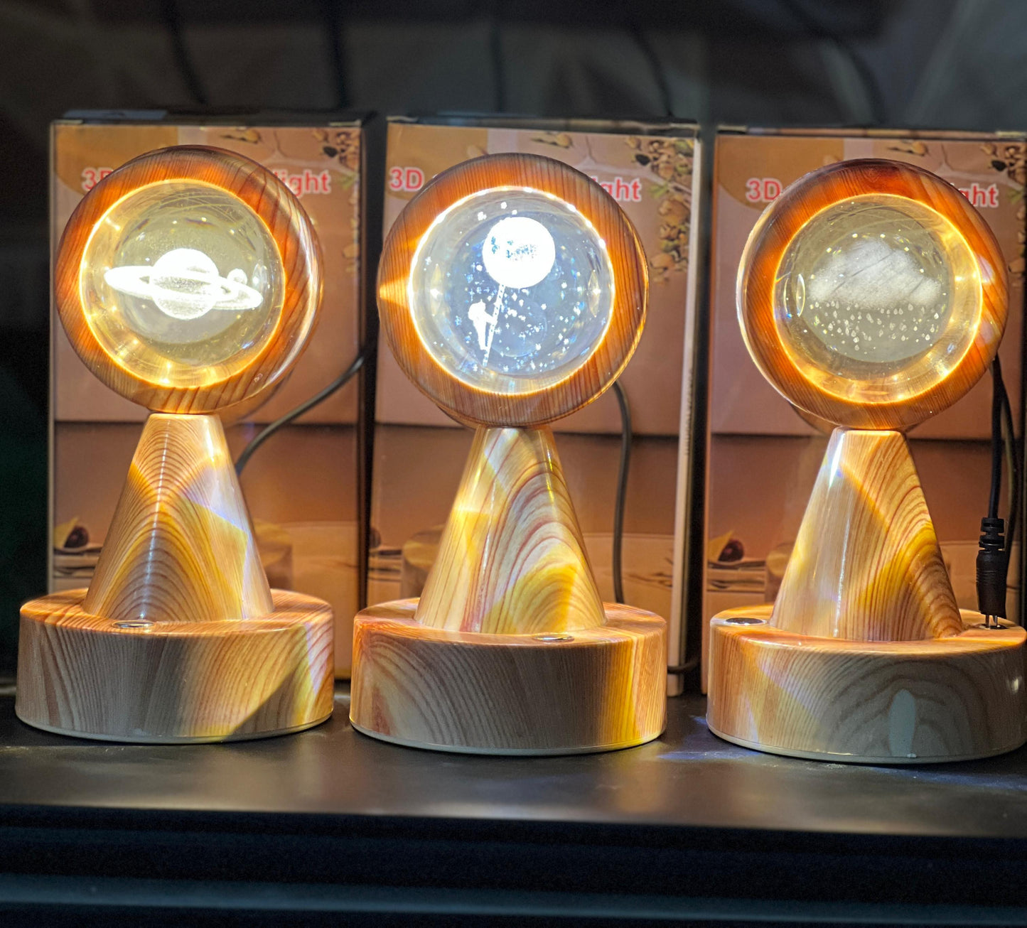 Three wooden crystal globe projector lamps displaying different planetary designs with glowing rings