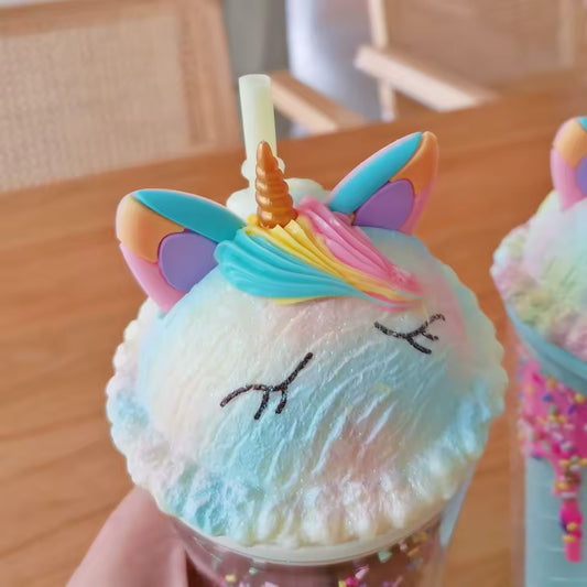 Colorful unicorn water cup with straw featuring rainbow horn and ears on whipped cream top