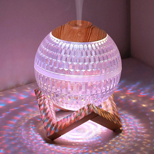 USB portable fragrance diffuser with textured spherical design and wooden top on wooden stand emitting mist and colorful light
