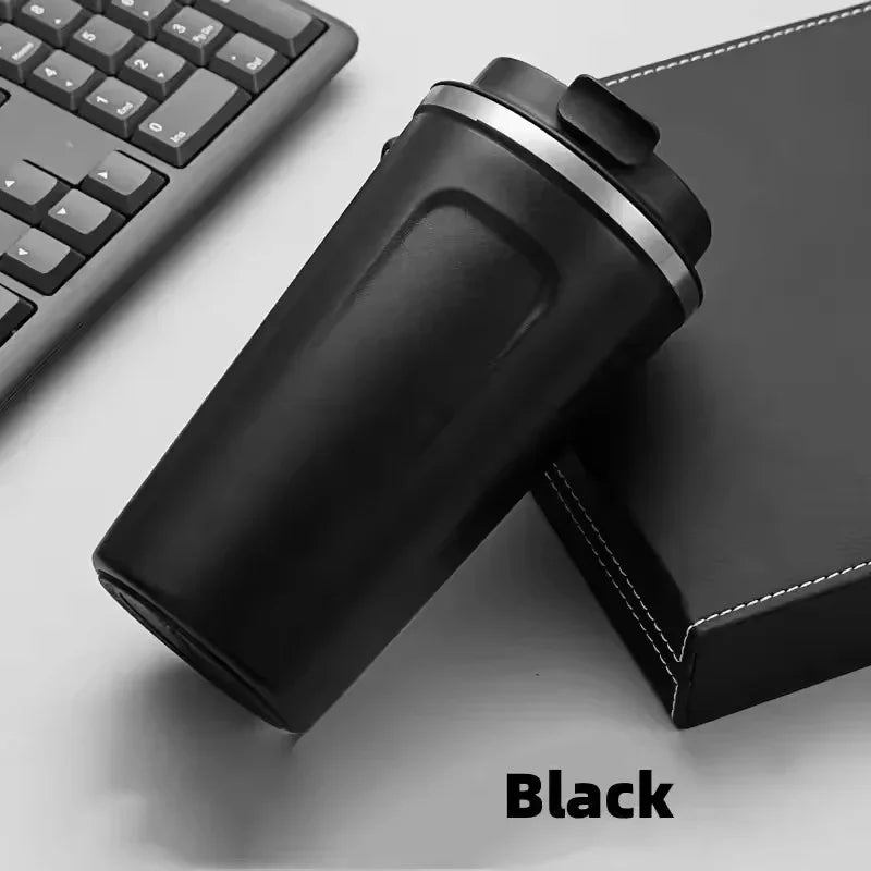 Black vacuum thermos bottle for tea and coffee placed next to a keyboard and a black notebook