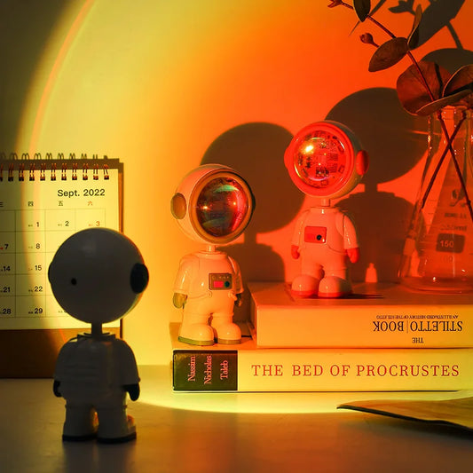 Astronaut starry sunset lamp casting orange glow on astronaut figures next to books and calendar