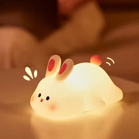 Cute rabbit desk lamp glowing warmly on a bedside table in a cozy bedroom setting