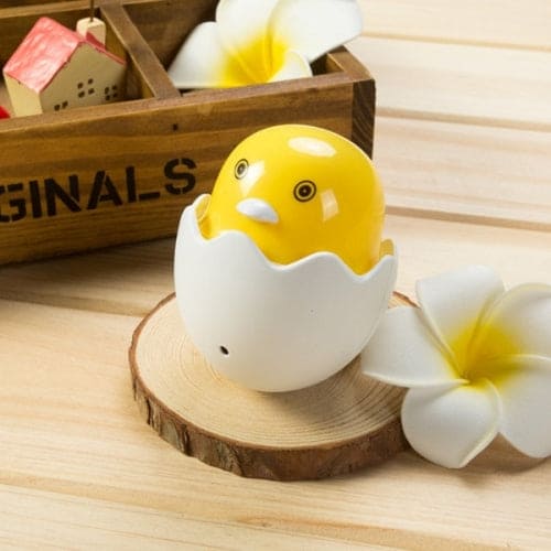 Cute yellow chick egg shell night lamp for bedroom placed on wooden surface with white flowers