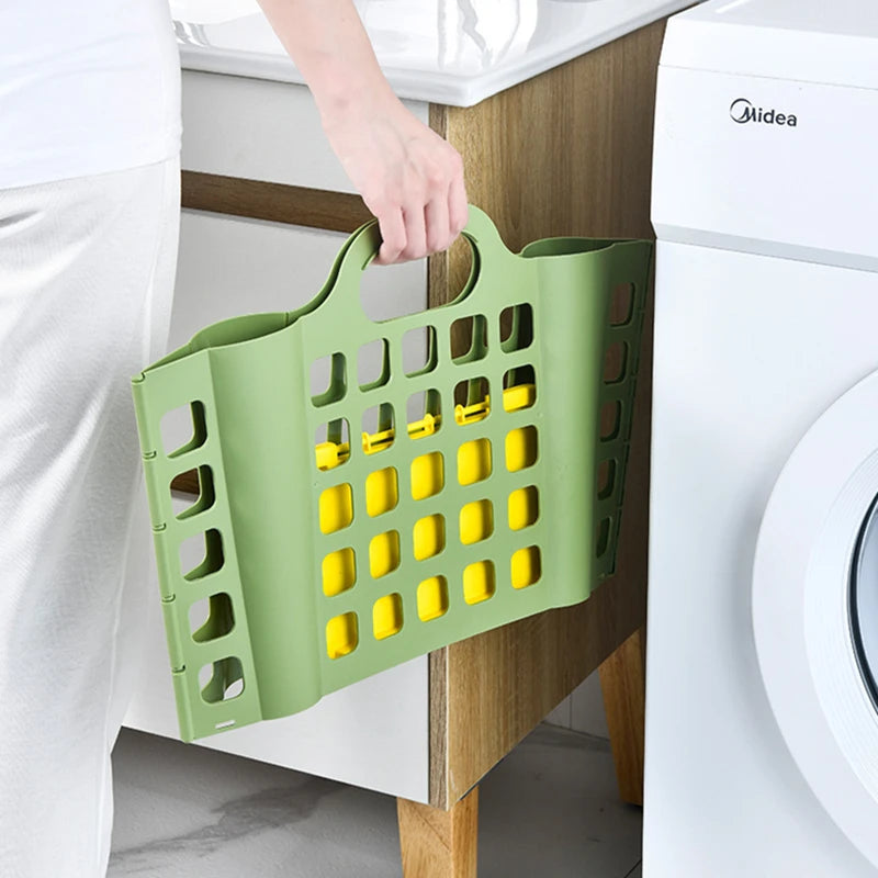 Green foldable plastic laundry basket being carried by hand near washing machine