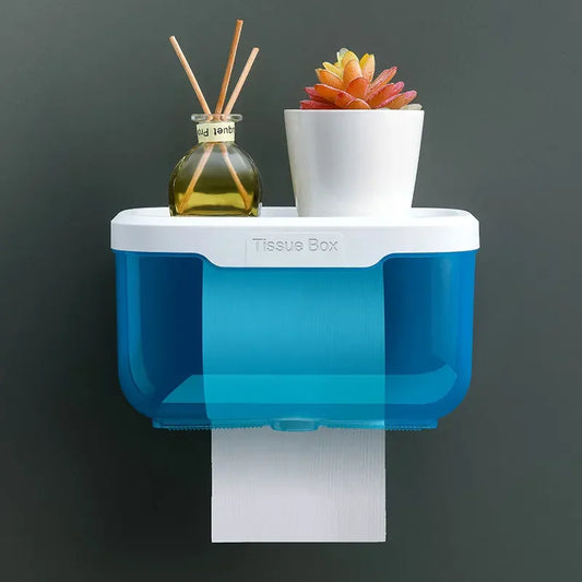 Blue and white wall mounted toilet paper holder with tissue box and small decorative items on top