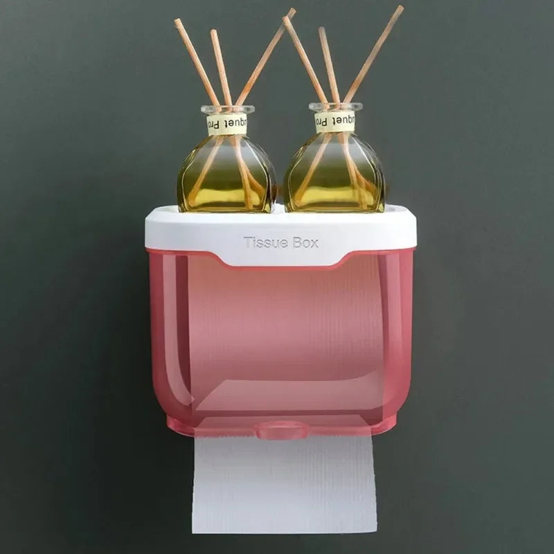 Wall mounted toilet paper holder in pink and white with top storage holding two reed diffuser bottles