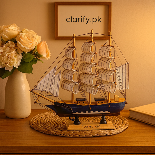 Vintage wooden ship showpiece with detailed sails on a wooden base displayed on a table beside a flower vase