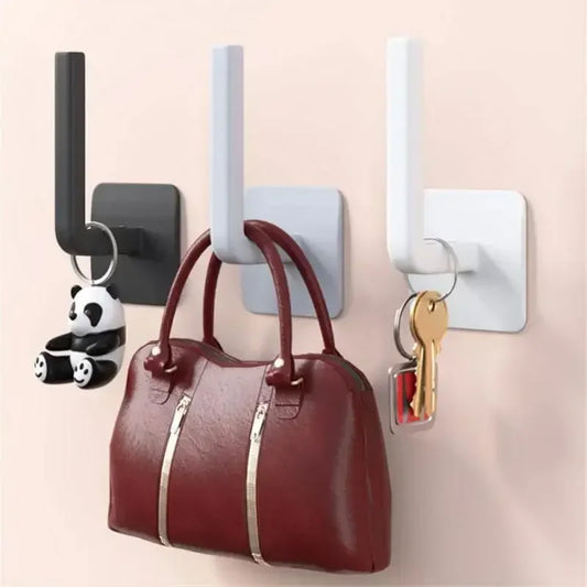 Set of black white and gray wall mounted paper towel holder hooks holding keys and a brown handbag