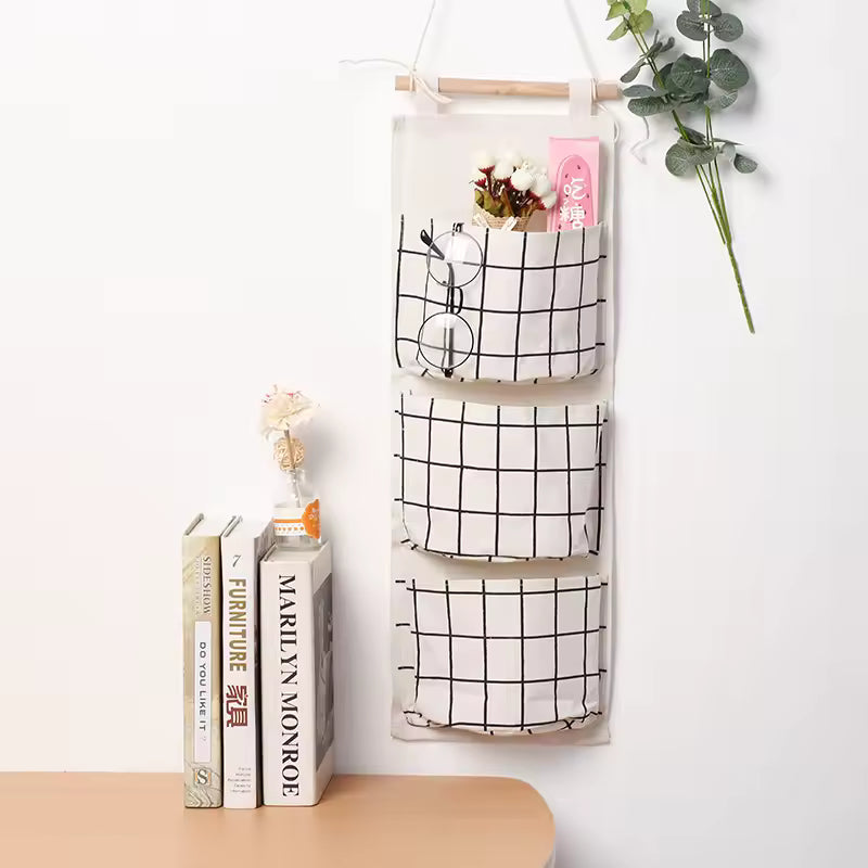 Clarify.pk hanging wall storage organizer with three black and white grid pockets holding glasses and small items