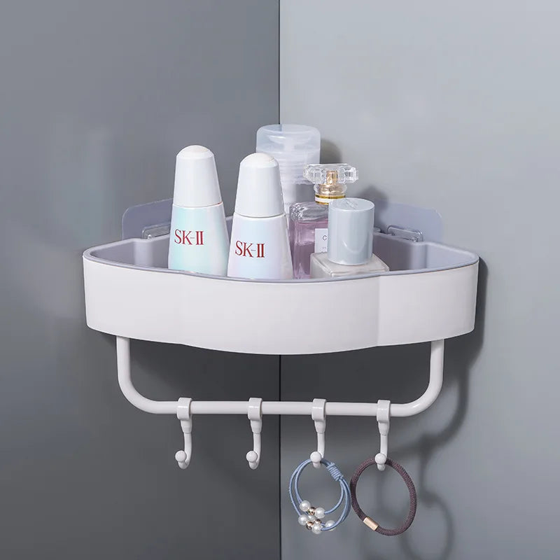 White wall-mounted corner shower shelf with hooks holding skincare bottles and accessories
