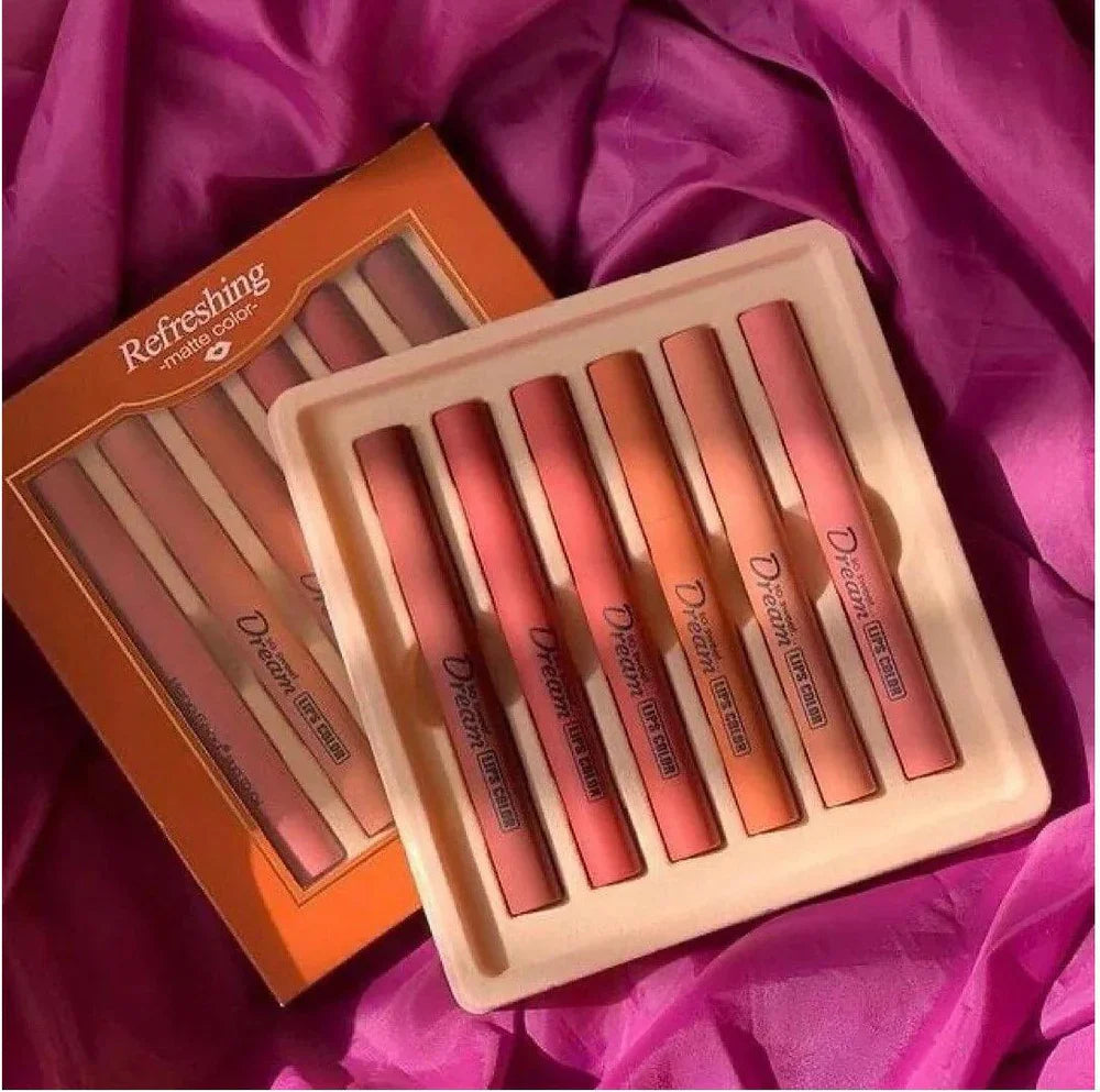 Cosmetics collection featuring a set of lipsticks in varying shades of pink and orange on a purple fabric background