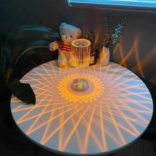 16 colors diamond lamp projecting intricate geometric patterns on a round white table with plants and teddy bear nearby