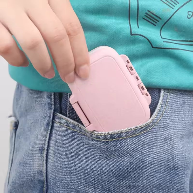 Pink 3 compartment pill box being placed into a blue denim pocket for easy portability