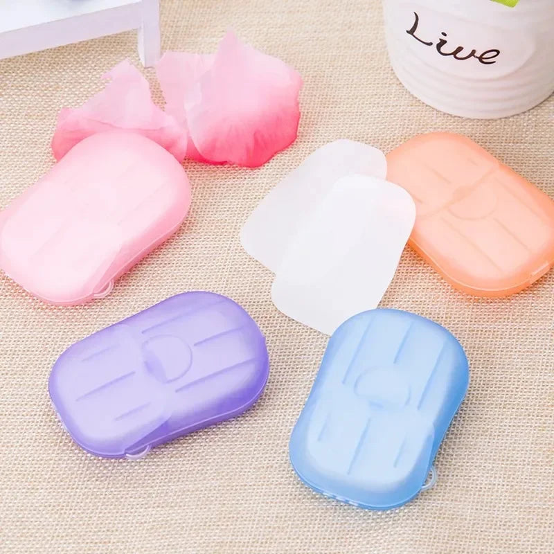 4 box travel soap paper sheets in pink, orange, purple, and blue compact cases on a beige surface