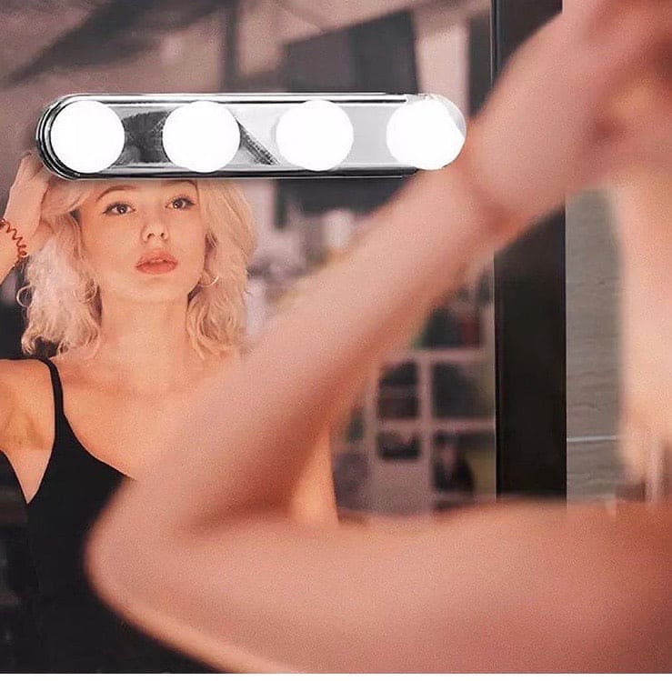 4 bulb makeup mirror light attached to mirror illuminating woman applying makeup