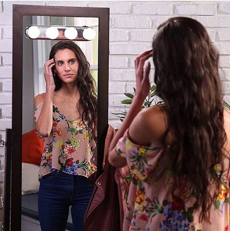 Woman using 4 bulb makeup mirror light mounted on wooden framed mirror for makeup application