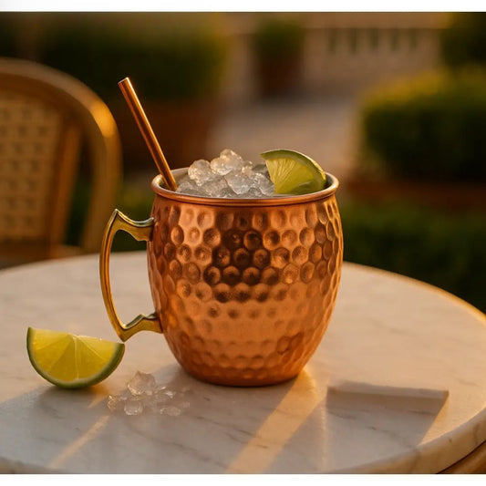Clarify.pk 500ml copper cocktail mug with hammered texture filled with ice and lime wedge on a marble table