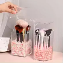 Clear acrylic cosmetic organizer holding makeup brushes with pink decorative beads inside