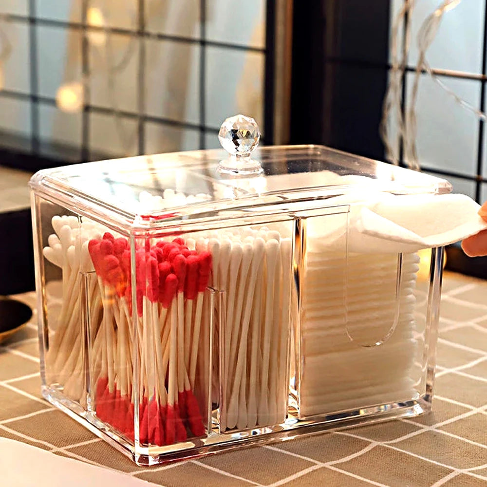 Clear acrylic cotton swab box with separate compartments holding white and red swabs and cotton pads
