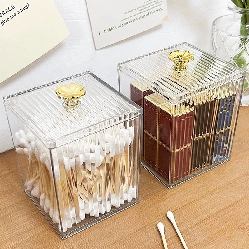 Clear acrylic makeup organizer cotton swab storage box with gold handle on wooden surface