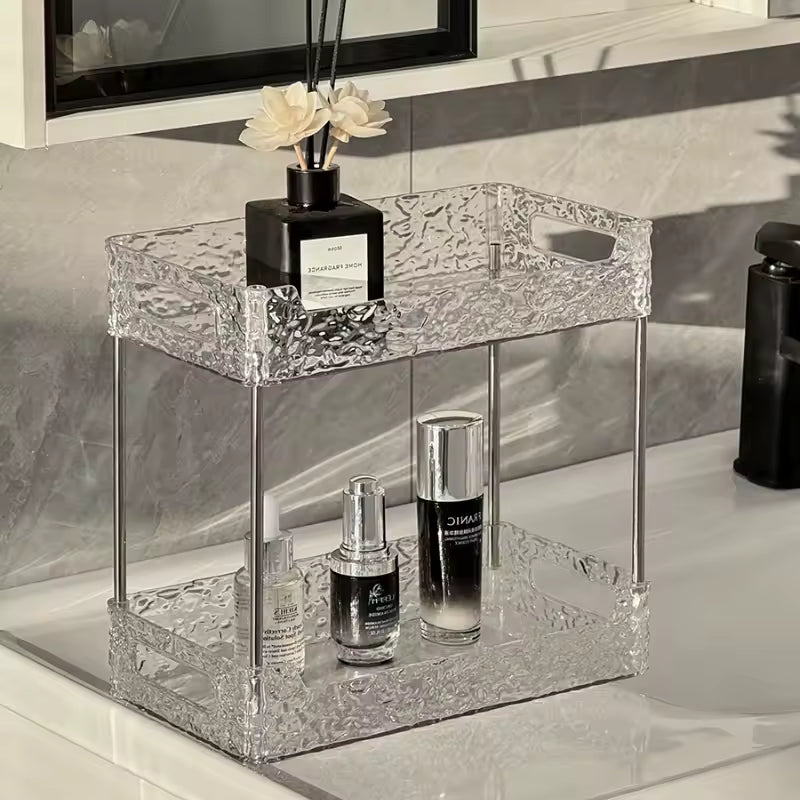 Clear two-tier acrylic shower organizer with textured design holding perfume and skincare bottles