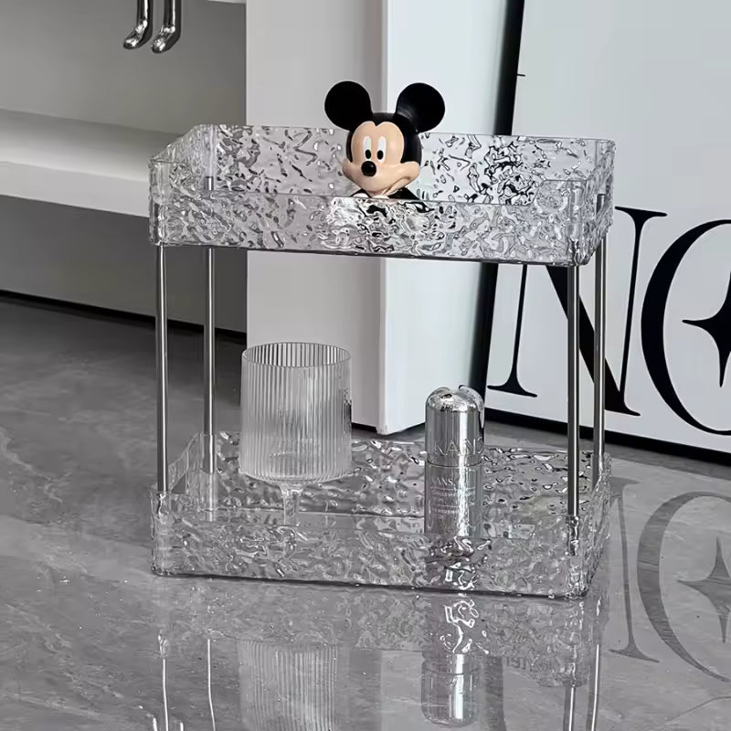 Clear acrylic shower organizer with two shelves holding a Mickey Mouse figure and bathroom accessories