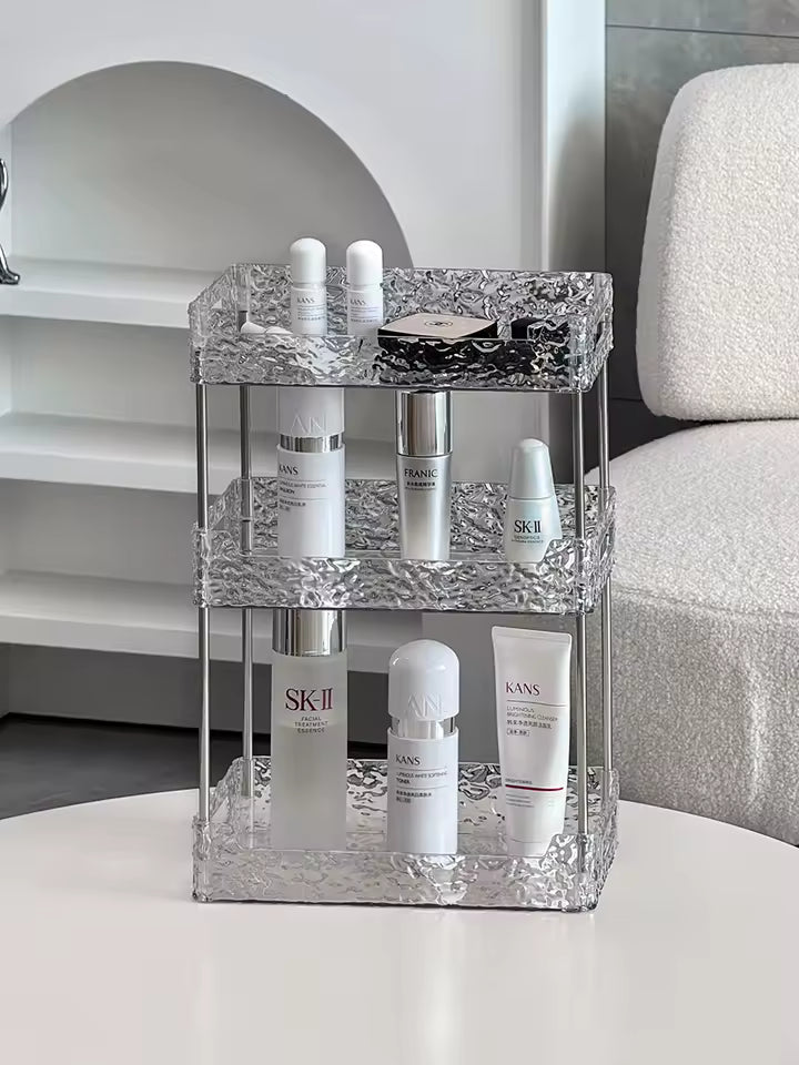 Three-tier acrylic shower organizer with textured design holding skincare bottles on a white table