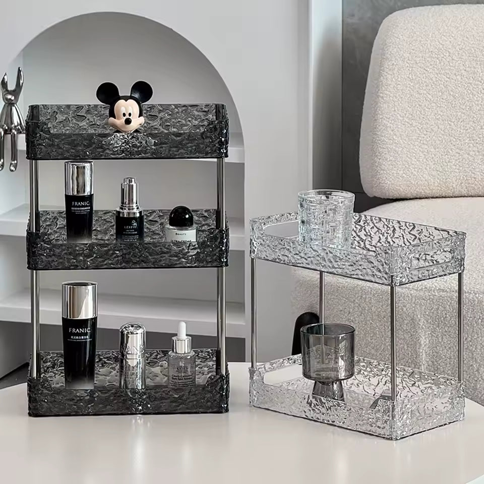 Black and clear acrylic shower organizer racks with three and two tiers holding bottles and accessories