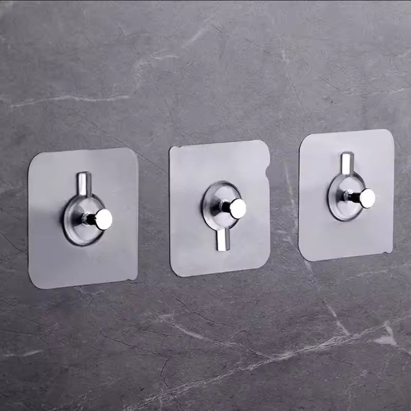 Set of three stainless steel adhesive wall hooks for home mounted on a gray marble surface