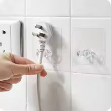 Clear adhesive wall storage hook holding a white electrical plug on a tiled wall