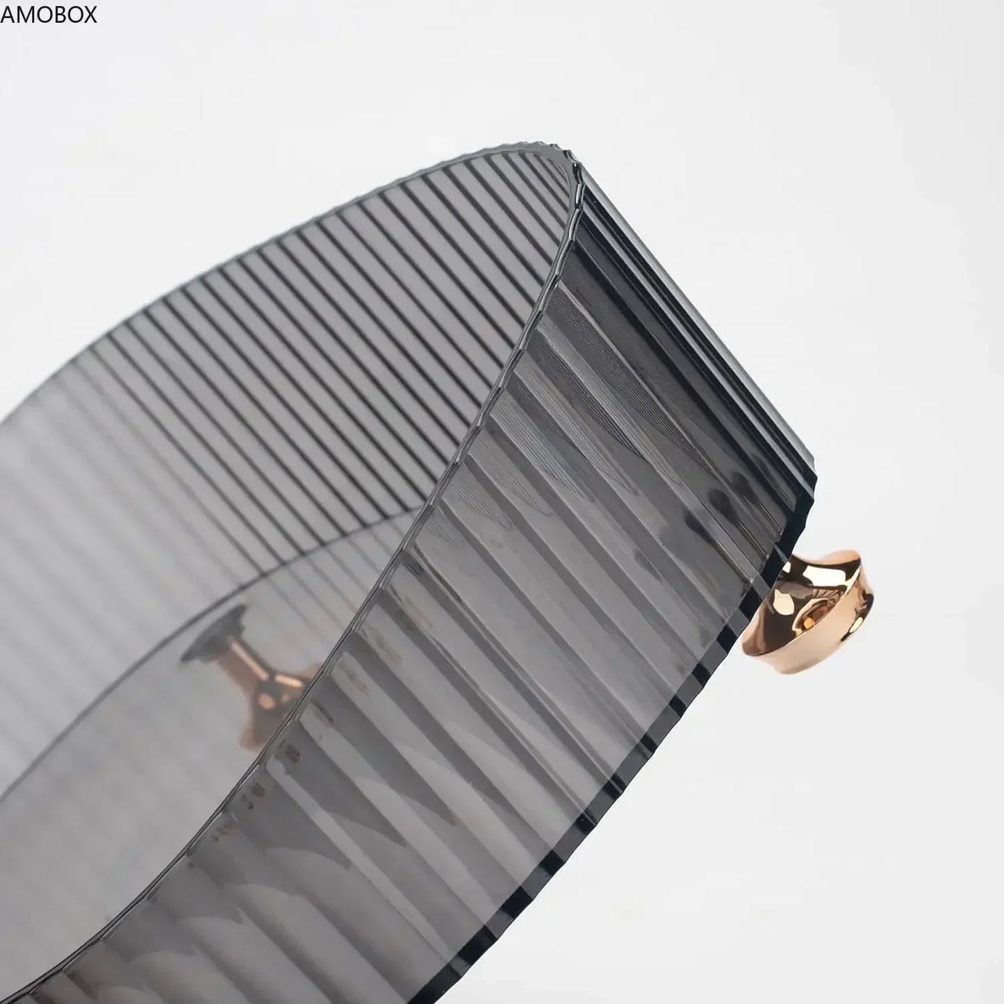 Close-up of a black ribbed transparent dresser storage box with a gold knob handle