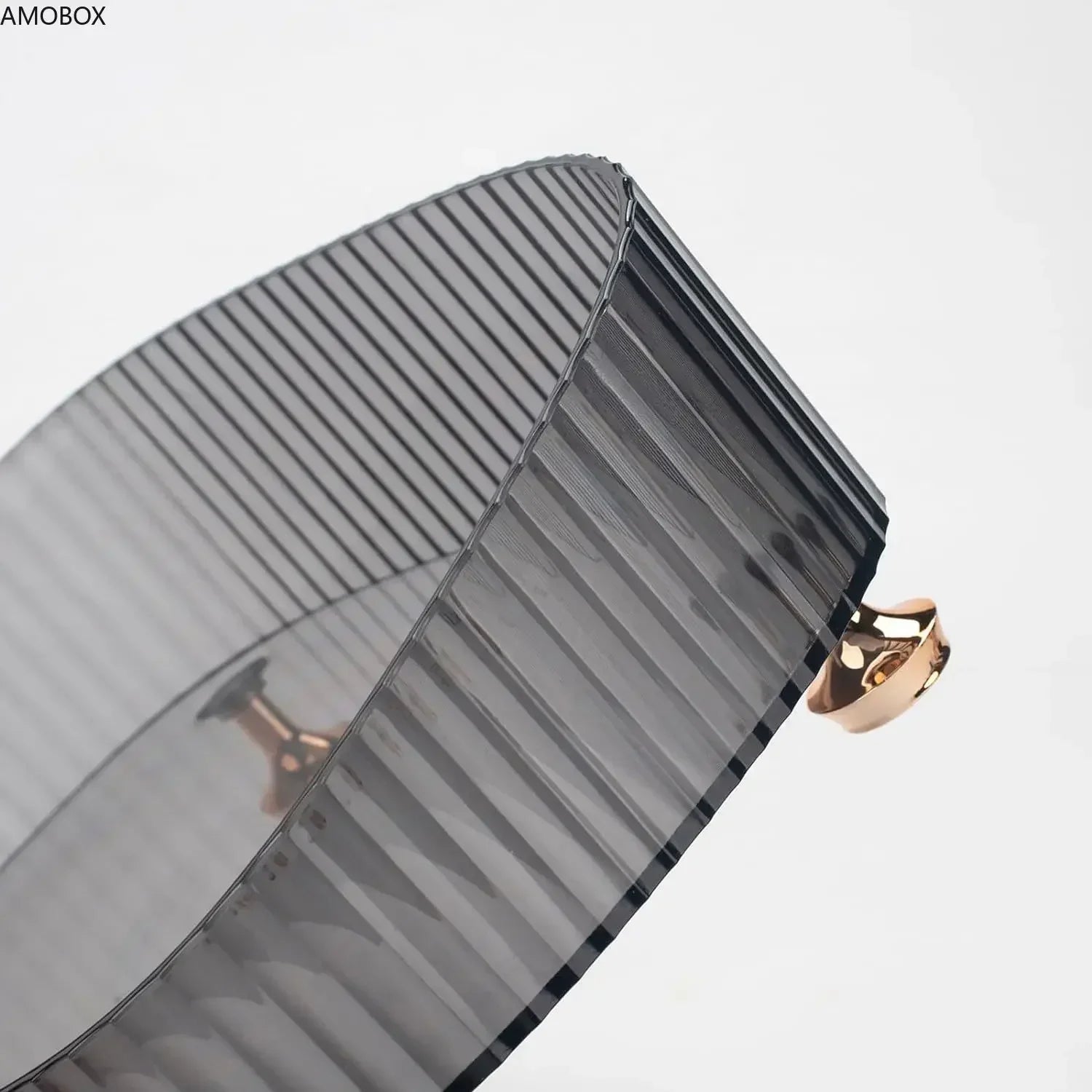 Close-up of a black ribbed transparent dresser storage box with a gold knob handle