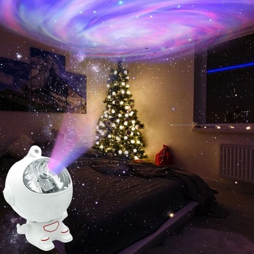 Astronaut star projector lamp casting colorful galaxy lights on bedroom ceiling with Christmas tree in background