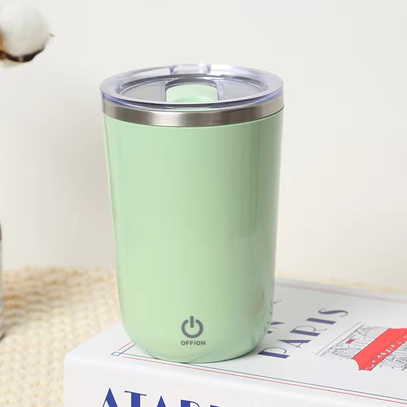Clarify.pk green automatic self stirring mug with clear lid and power button on a book