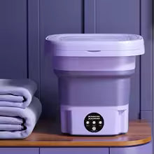 Clarify.pk folding washing machine in purple compact design placed on wooden surface with folded towels