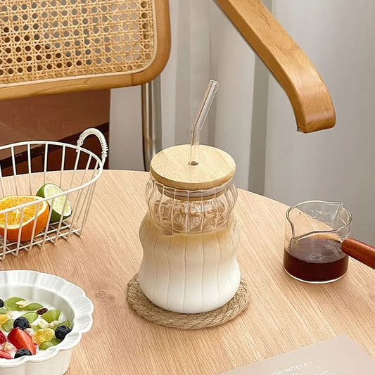 Clear glass mug with frosted bottom and bamboo lid glass mug with straw on wooden table