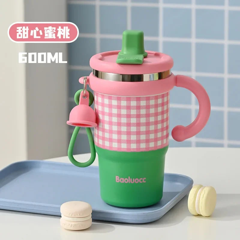 600ml stainless steel kids thermos with pink and green checkered design and handle on blue tray