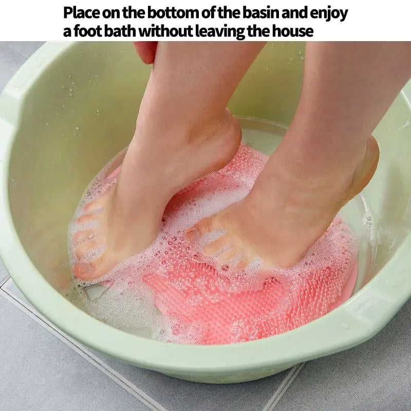 Person using pink silicone foot scrubber pad in green basin for a relaxing foot bath at home