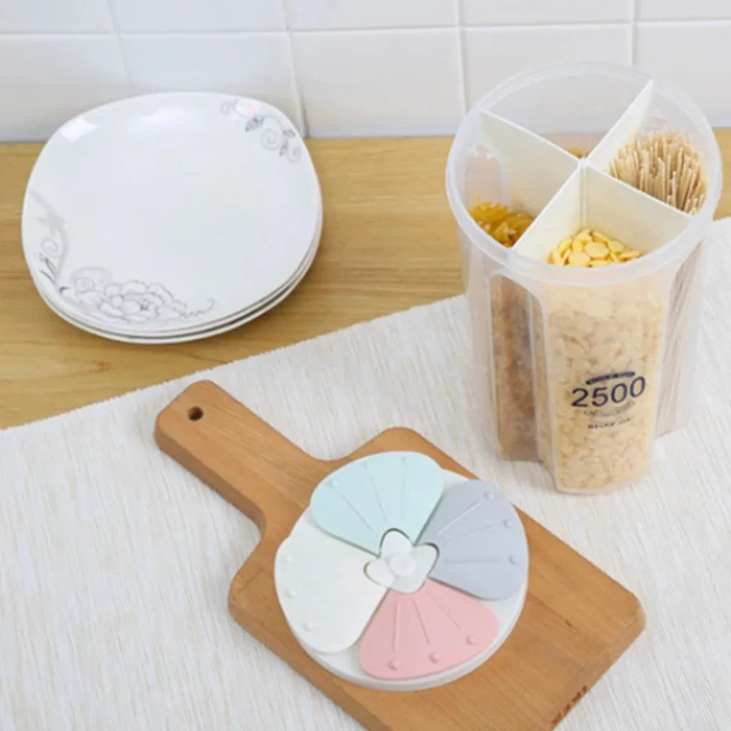 Clear plastic grain storage container with four compartments on kitchen counter next to plates and cutting board