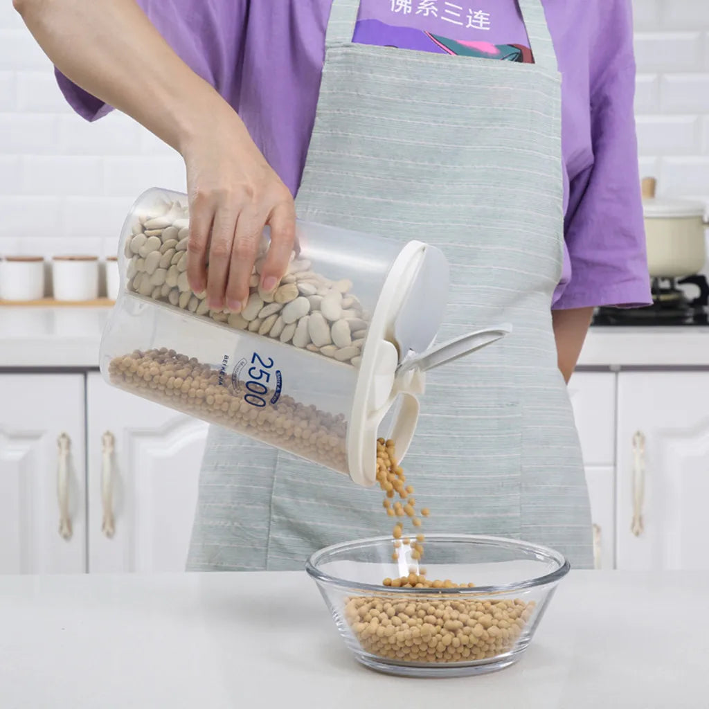 Person pouring beans from a clear grain storage container with dual compartments into a glass bowl