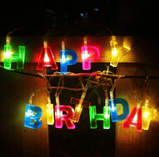 Colorful birthday decoration string lights spelling HAPPY BIRTHDAY hanging on a wooden surface