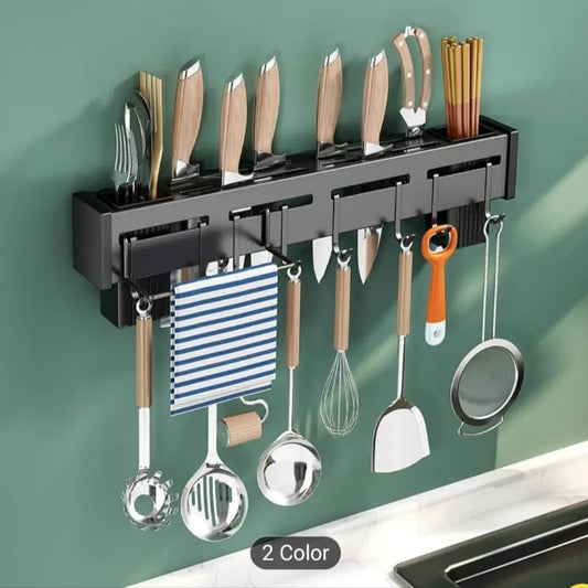 Black wall mounted knife holder with knives, kitchen utensils, and storage compartments on green wall