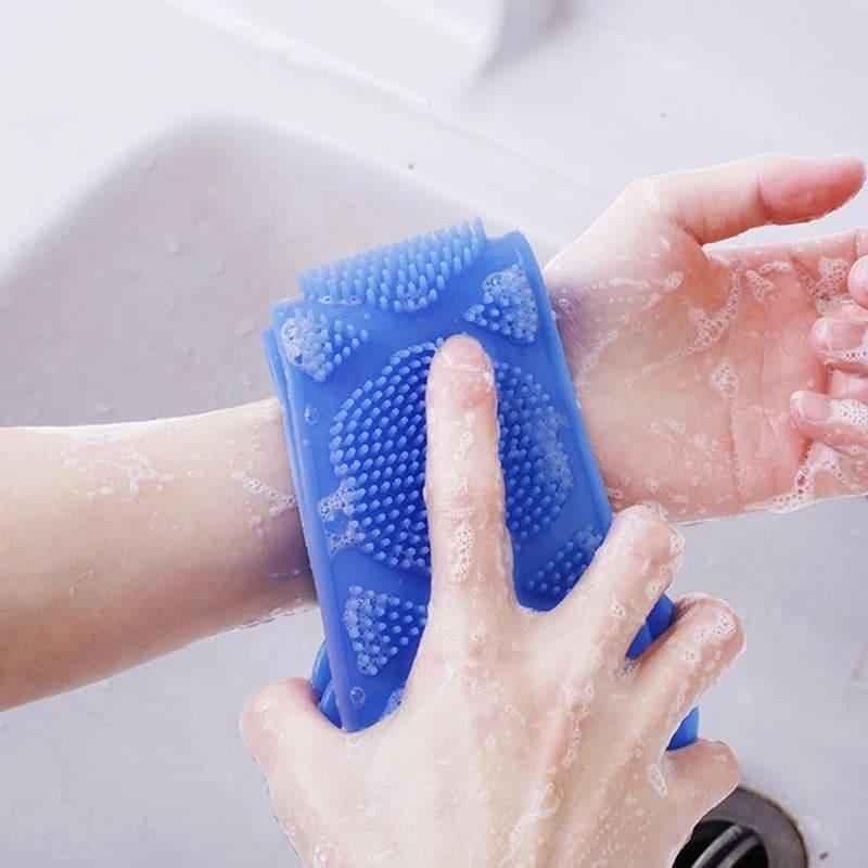 Blue silicone body scrubber with textured bristles being used to clean a wrist under running water