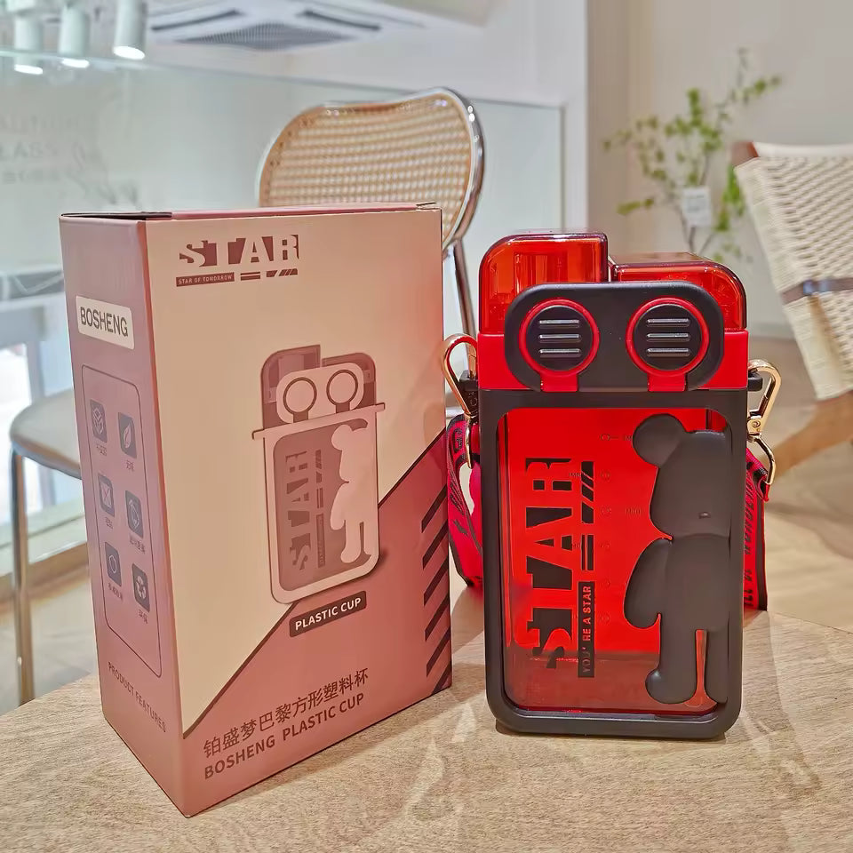 Red cartoon bear water bottle with black bear design and carrying strap next to its box by Clarify.pk