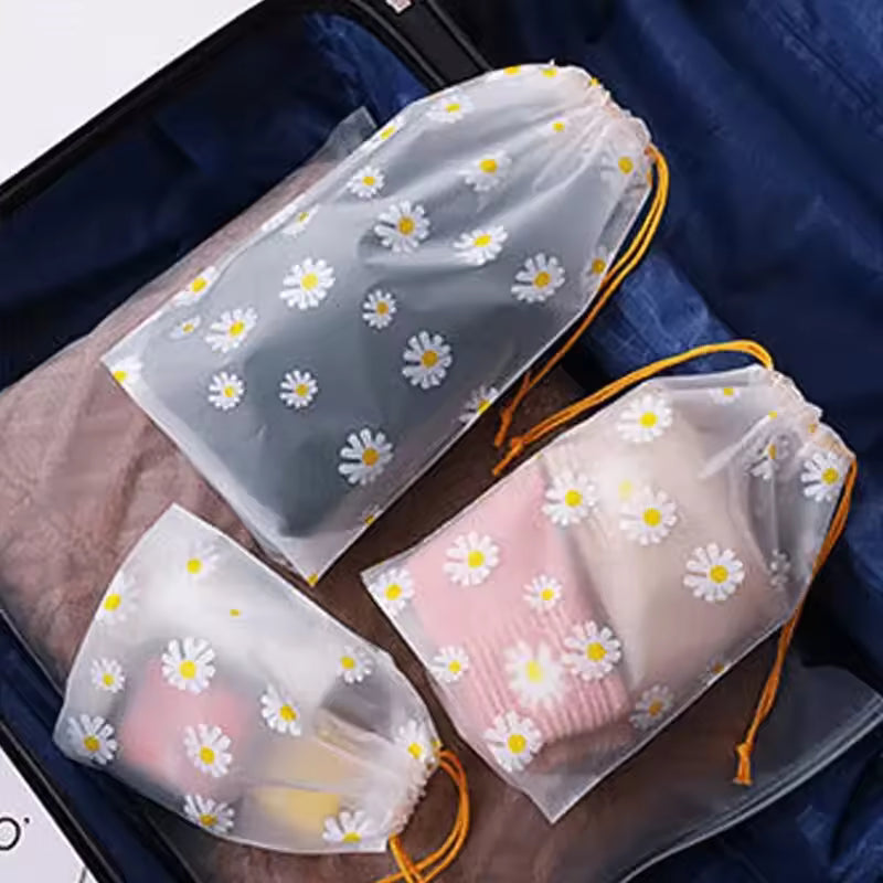 Clarify.pk 4 piece travel storage bags with daisy print and yellow drawstrings packed in a suitcase