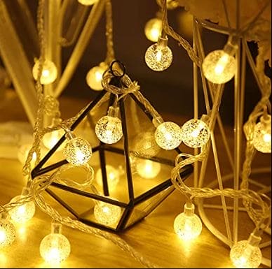 Warm glowing bubble ball LED string lights wrapped around black geometric decor piece