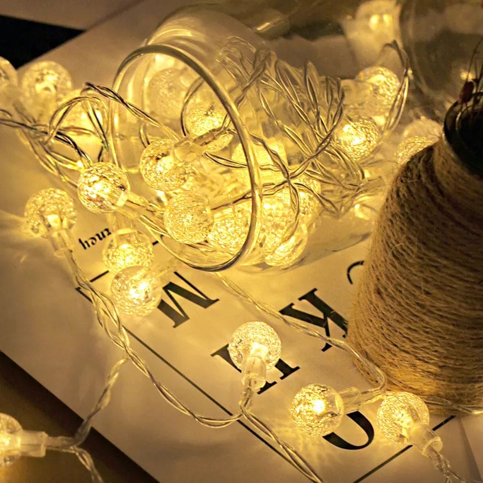 Warm white bubble ball LED string lights glowing inside a clear jar on a table