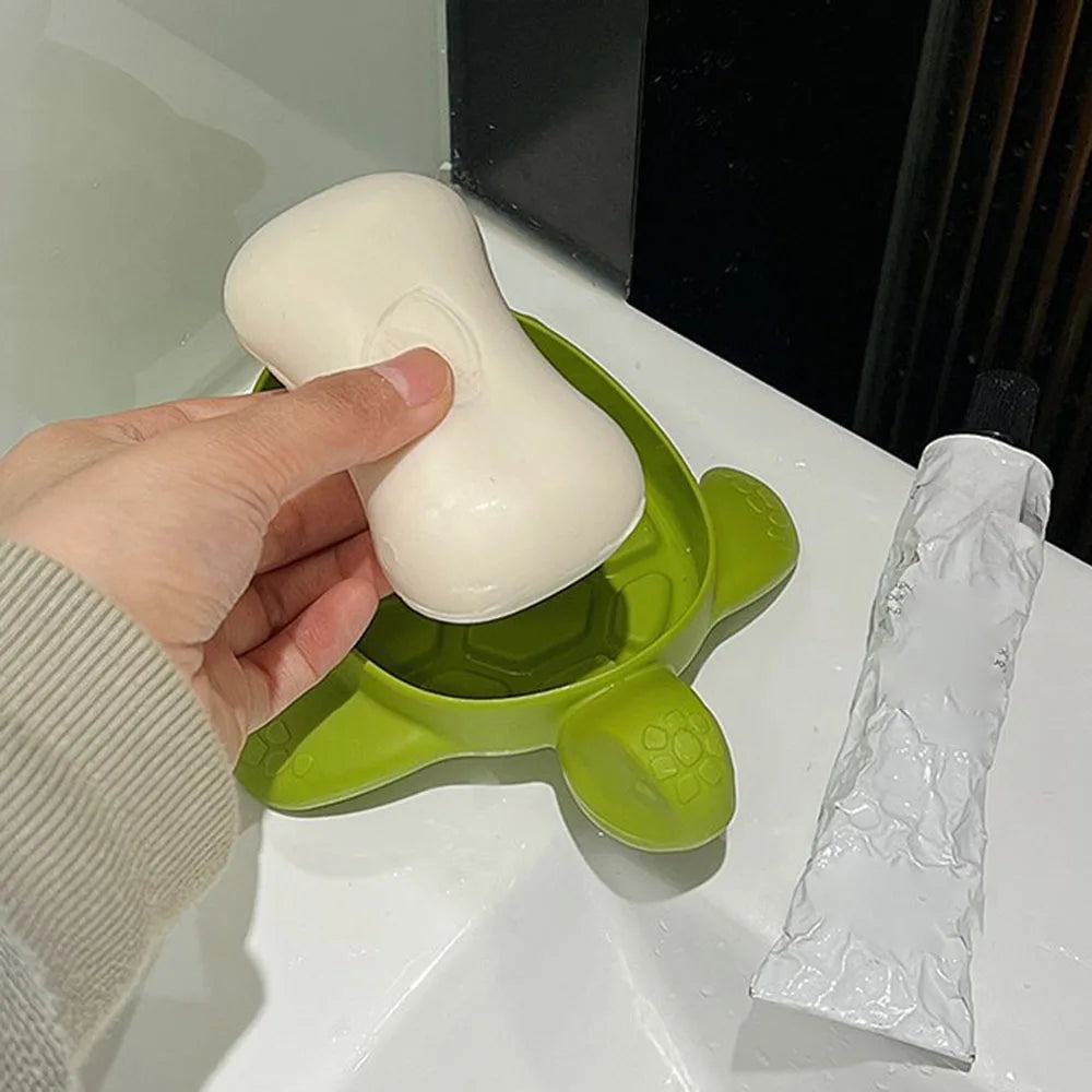 Hand placing white soap on green cartoon turtle soap holder on bathroom sink by Clarify.pk