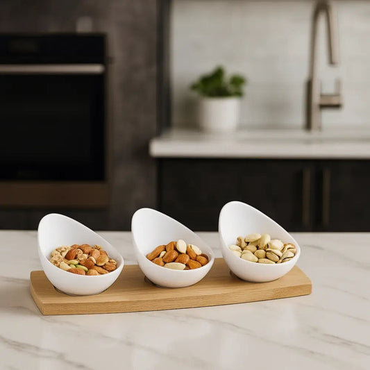 White ceramic snack bowl set with mixed nuts on a wooden tray placed on a kitchen countertop
