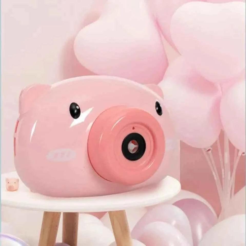 Pink pig-shaped children's bubble machine toy on a wooden stool with heart-shaped balloons background